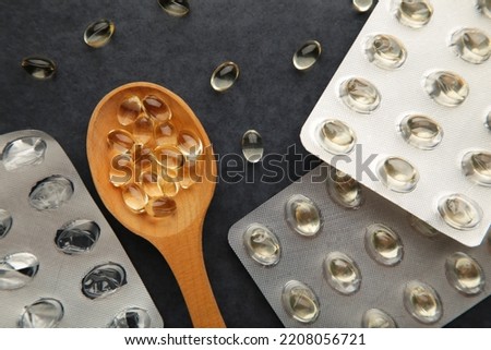 Vitamin D yellow pills on wood spoon on dark background. Medicine tablets of vitamin d on table. Top view