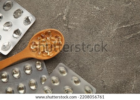 Vitamin D yellow pills on wood spoon on grey background. Medicine tablets of vitamin d on table. Top view