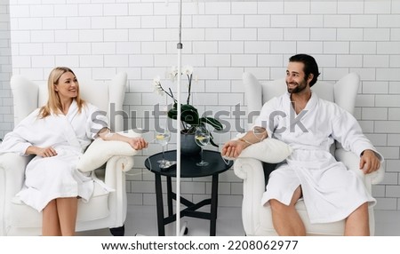 Maintenance and restoration of human immune system with vitamin IV infusion therapy. Beautiful woman with her boyfriend in modern wellness center during intravenous vitamin therapy. Royalty-Free Stock Photo #2208062977