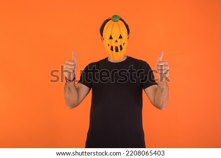 Person with pumpkin mask celebrating Halloween, giving thumbs up. Concept of celebration, All Souls' Day and All Saints' Day.