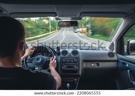 A male driver drives at speed through the streets of the city, a view from inside the car. Royalty-Free Stock Photo #2208065555