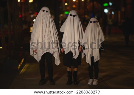 A man dressed in a ghost costume with glasses walks around the city. Halloween holiday. Masquerade. Ghost concept. Article about Halloween. Ghost article. Mystic