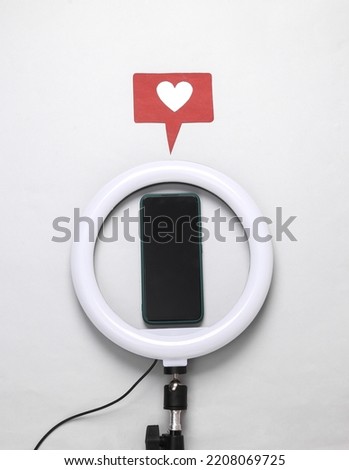 Led ring lamp with smartphone and like icon on a gray background. Gear for blogging and vlogging. Top view