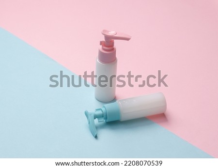 Bottles of cream or liquid soap with a dispenser on a blue-pink pastel background. Creative beauty still life