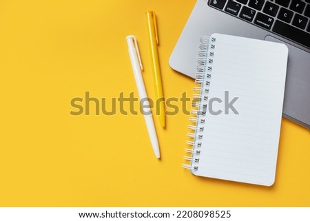 Yellow office desktop background with mockup empty notepad, modern laptop, pens and empty place for copy space. Freelance or working at home concept.