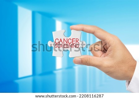 Cancer screening. Hand holding jigsaw puzzle piece with Cancer screening text.