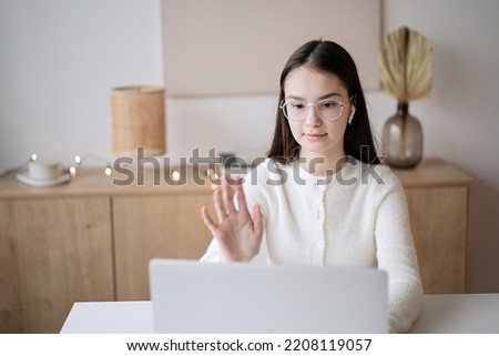 Cute teenager girl sitting at table with books and doing homework. Education concept, distance learning, self-education, video conference class with tutor                                