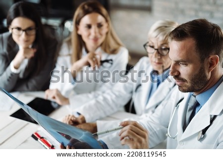 Group of doctors analyzing medical scan with businesswoman  in the hospital