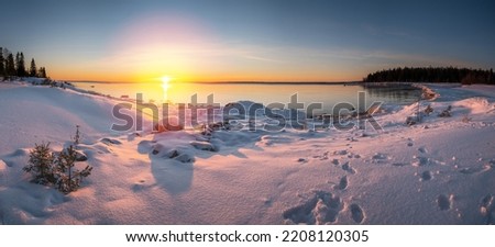 Panoramic sunset through the horizon. Winter wonderland scenery in scenic golden evening light at sunset with clouds and long shadow. tranquil nature copy space background.