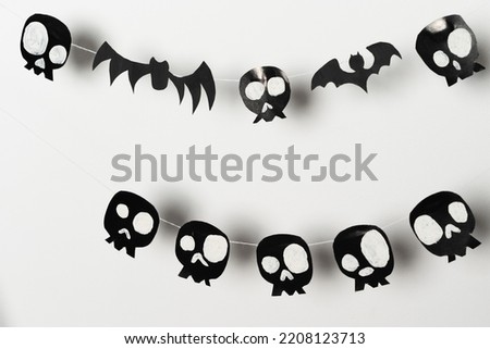 Bats and skulls black on a white background, place to write a greeting, paper craft for Halloween.