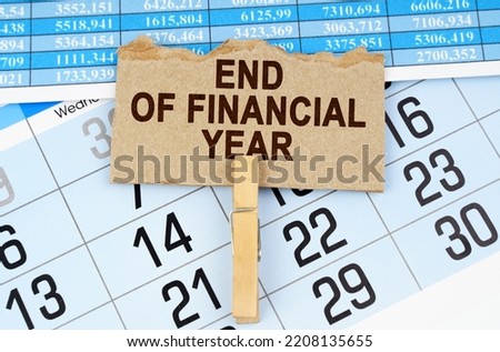 Business concept. On the calendar and reporting documents is a cardboard plate with the inscription - END OF FINANCIAL YEAR