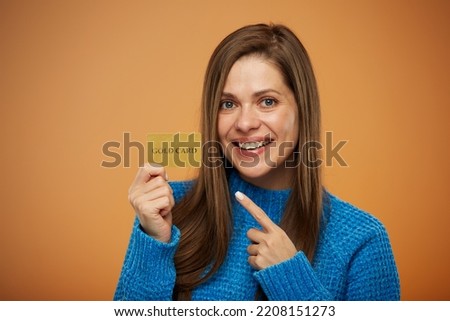 Smiling woman holding credit card and pointing finger. Girl ready for online shopping. Isolated female portrait.