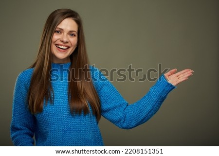 Smiling woman in casual blue warm sweater holding empty hand. Isolated female portrait.