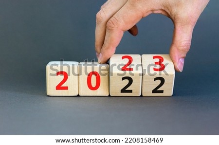 2023 happy new year symbol. Businessman turns cubes, symbolize the change from 2022 to the new year 2023. Beautiful grey background. Copy space. Business and 2023 happy new year concept.