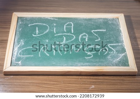 Green chalkboard with the word "Children's Day" written in Portuguese phrase white chalk.