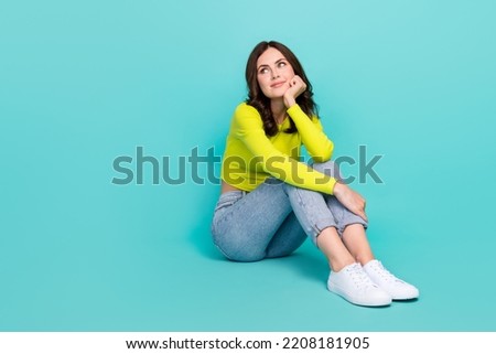 Full length portrait of minded lovely person sit floor hand touch cheek look empty space isolated on cyan color background Royalty-Free Stock Photo #2208181905