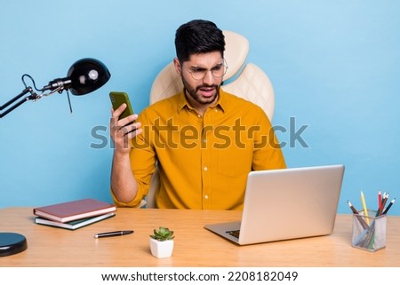 Photo of impressed person sitting chair hold telephone use wireless netbook isolated on blue color background