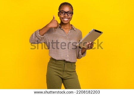 Photo of sweet positive woman wear plaid shirt eyewear reading modern gadget thumb up isolated yellow color background
