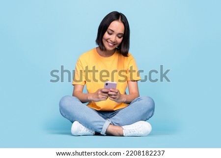 Full body size photo of young korean pretty cute nice girl sitting hold new smartphone user addicted typing instagram followers isolated on blue color background