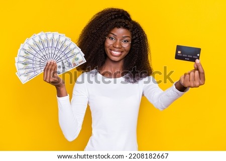 Photo of pretty positive person arm hold demonstrate plastic debit card dollar banknotes isolated on yellow color background