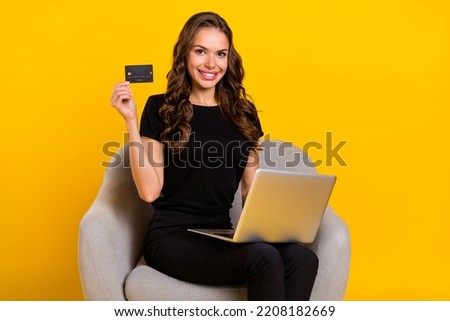 Photo of young cheerful lady sit armchair shop salary use laptop advertise retail isolated over yellow color background