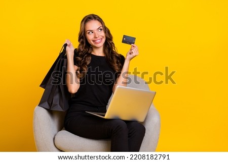 Photo of young girl dreamy curious look empty space make shopping use laptop isolated over yellow color background