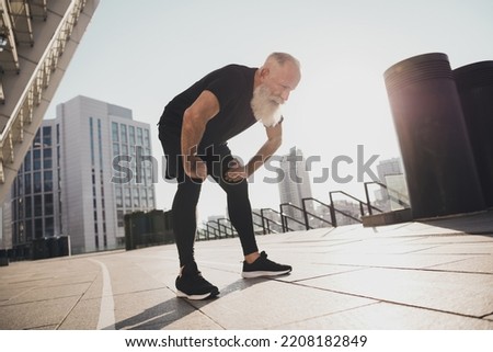 Photo of tired exhausted sportive pensioner man take break catch heavy breath sunset training urban town outdoors
