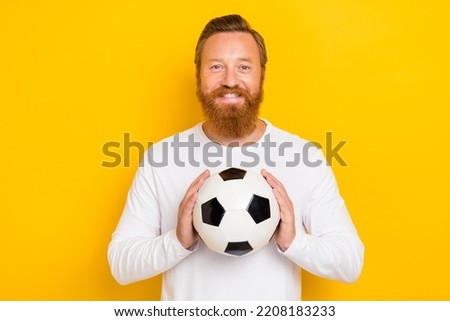 Photo of satisfied glad person arms hold football toothy smile isolated on yellow color background
