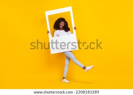 Full size photo of excited carefree girl hold paper album card good mood isolated on yellow color background