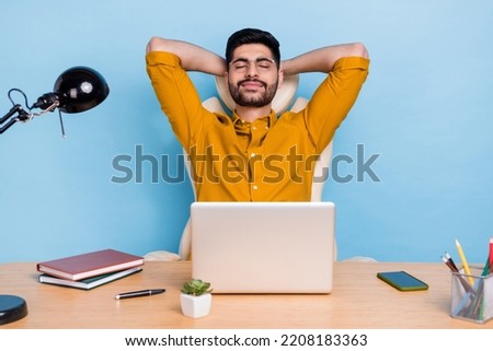 Photo of peaceful handsome guy sit chair hands behind head closed eyes relax isolated on blue color background