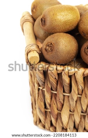 Harvest kiwi in a wicker basket on white background. Close-up. Space for text.