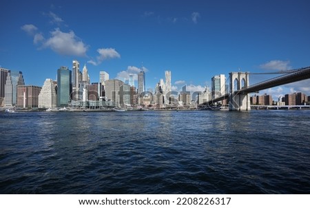 View from a boat to East River with Manhattan and Brooklyn bridges landmark and other iconic buildings from New York City during a beautiful sunny day.