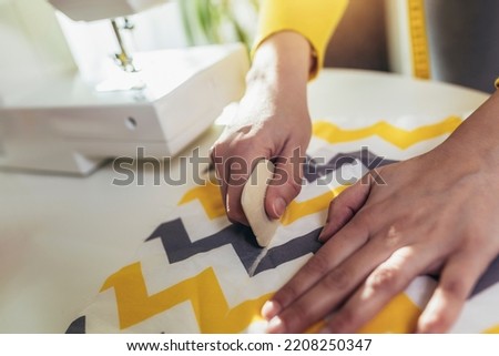 Woman sewing on a sewing machine at her home, close up.