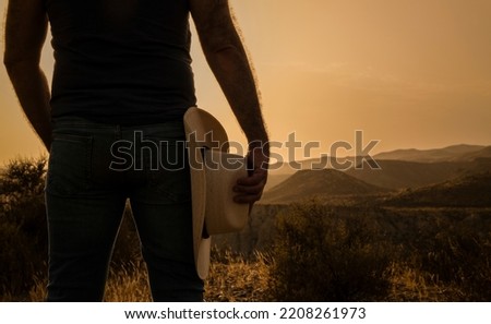 Silhouette of adult man holding cowboy hat standing on desert during sunset. Almeria, Spain