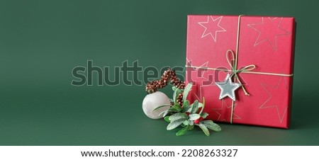 Gift box and Christmas decor on green background with space for text