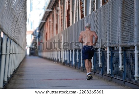 Run in the early morning. A bare-chested man running and jogging on the pedestrian path from Manhattan Bridge. Sport is good at any age.