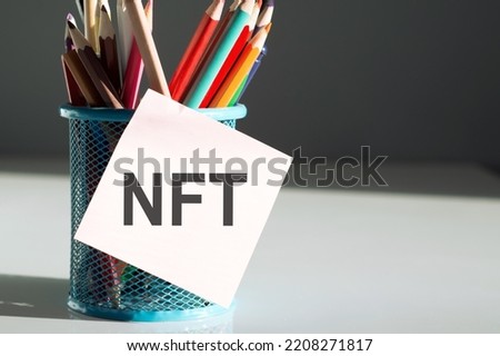 NFT text on sticky on cup of colorful pencils