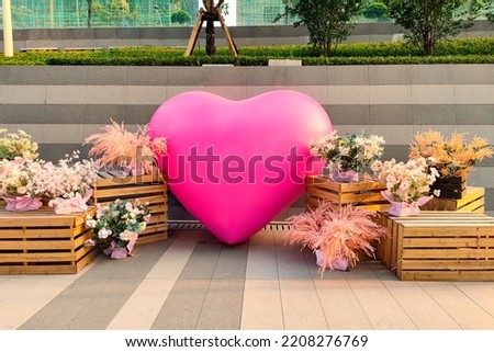 Outdoors a pink heart-shaped inflatable ball with a bouquet