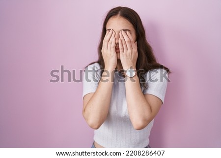 Young hispanic girl standing over pink background rubbing eyes for fatigue and headache, sleepy and tired expression. vision problem 