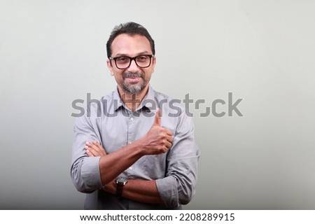 Middle aged happy man of Indian origin showing thumbs up gesture Royalty-Free Stock Photo #2208289915