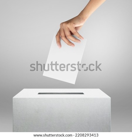 Election vote, hand holding ballot paper for election vote concept at grey background. Royalty-Free Stock Photo #2208293413