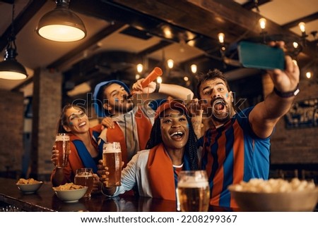 Group of happy soccer fans having fun while taking selfie in bar during the world championship.