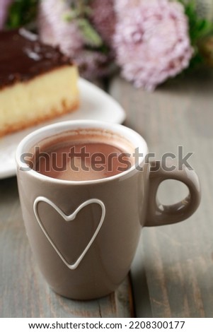 Cup of hot chocolate and cheese cake in the background. 