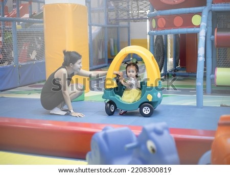 Pretty little kid girl in dress sit on toy at theme park, playing with toys. beautiful baby girl and her mom sitting play toys on blur background. Quality picture. concept happy mom and daughter.