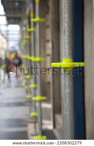 Detail of yellow elements holding scaffolding tubes of a city building renovation scaffolding
