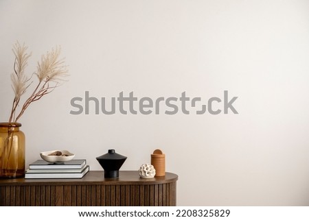 Minimalist composition of living room interior with copy space, wooden stripes commode, vase with dried flowers, candle, black books and personal accessories. Home decor. Template.  Royalty-Free Stock Photo #2208325829