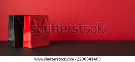 Black friday sales concept. Photo of red and black paper bags on black desktop red wall background with empty space