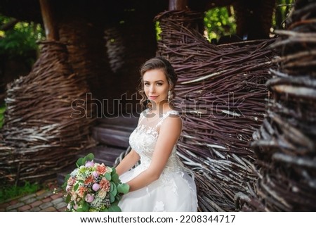 Portrait of the bride. A young girl in a white wedding dress with a bouquet of flowers in her hands on a background of a forest at sunset