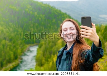Happy woman takes a selfie on the background of mountains and multinsky lake. Empty space for text