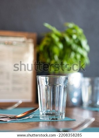 Table setting in a restaurant, drinking glass and cutlery, partial view, selective focus, blurred effect